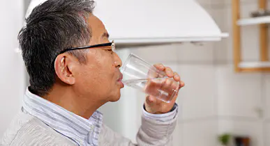 コップで水を飲む男性